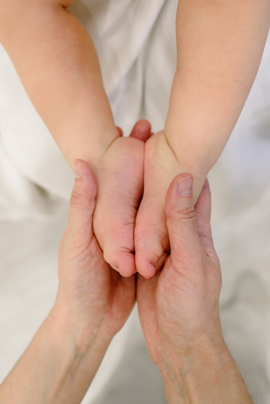 Mains adultes tenant délicatement les pieds d'un nouveau-né