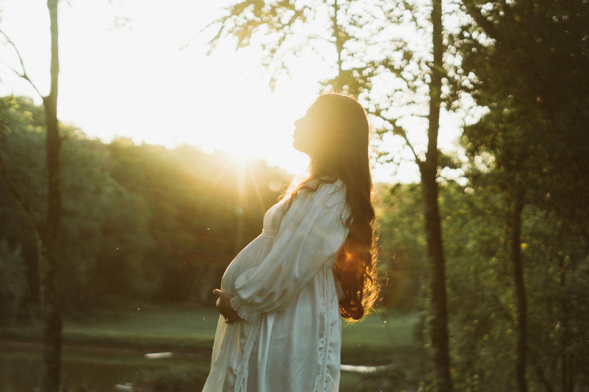 Femme enceinte de profil dans la lumière dorée d'un coucher de soleil